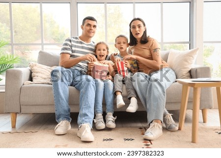 Shocked family with popcorn watching movie at home