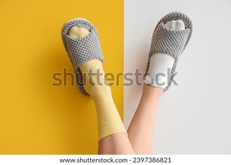 Female legs in soft slippers on yellow and white background Royalty-Free Stock Photo #2397386821
