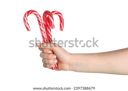 Female hand with Christmas candy canes on white background