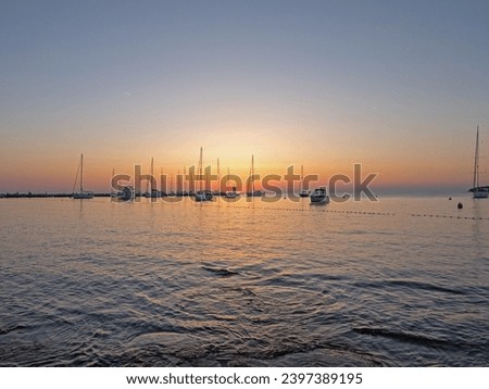 Picture of a marina with sailing ships in the backlight of the setting sun in summer