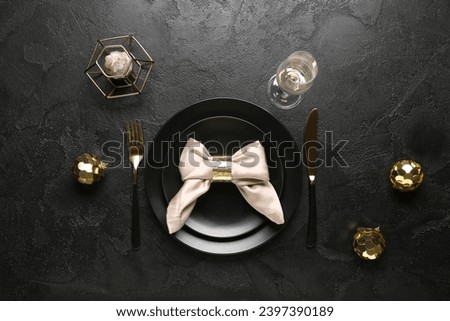 Beautiful table setting with Christmas balls and candle on black background