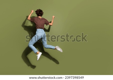 Full body photo of attractive young woman back view running jump dressed stylish brown clothes isolated on khaki color background
