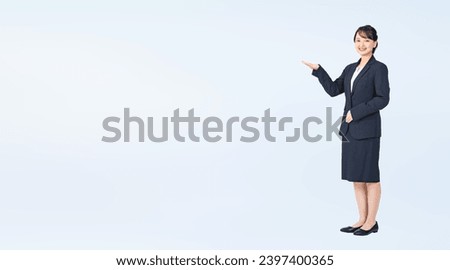 Guiding Asian woman wearing business suits. Wide angle visual for banners or advertisements. Royalty-Free Stock Photo #2397400365
