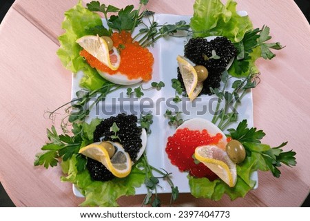 Luxurious appetizer of quail eggs with a paste of squid, shrimp and black caviar on potato and cheese chips