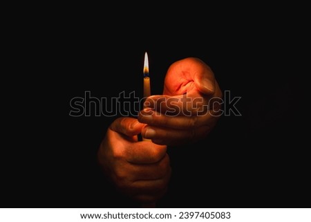 Burning candle in male hand, religion concept.Black background.Copy space.