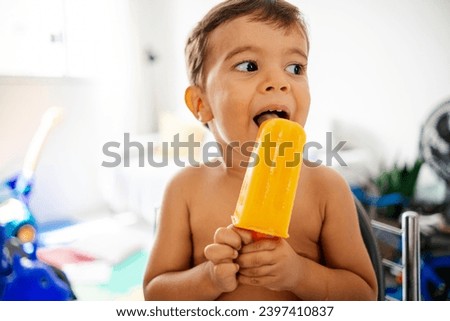 Baby enjoys a cool treat at home, savoring a healthy popsicle for relief from the heat Royalty-Free Stock Photo #2397410837