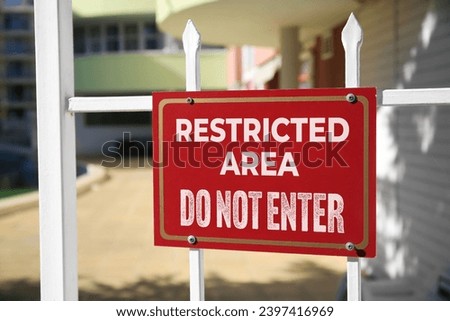 Sign with text Restricted Area Do Not Enter on fence outdoors