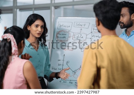 young girl at office discussing about project to team members or colleagues during meeting - concept of leadership presentation, workplace communication and startup culture. Royalty-Free Stock Photo #2397427987