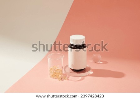 Vitamin E capsules were contained in a laboratory beaker, an unlabeled pill bottle was placed on a glass platform. Delicate pink background for dietary supplement advertising. Royalty-Free Stock Photo #2397428423