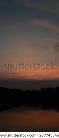 A picture of the twilight sky in a lake surrounded by trees