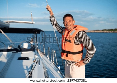 Mature man in a life jacket on a yach feeling good Royalty-Free Stock Photo #2397437381