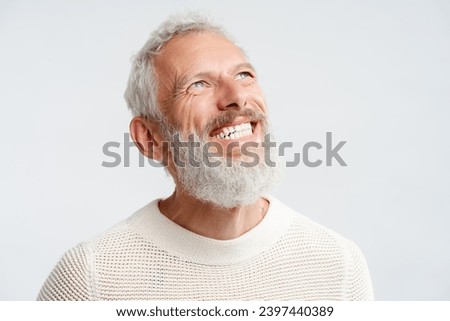 Portrait smiling handsome Scandinavian man with white teeth looking up isolated on white background. Health care, dental treatment concept. Happy gray haired bearded hipster after barbershop service Royalty-Free Stock Photo #2397440389