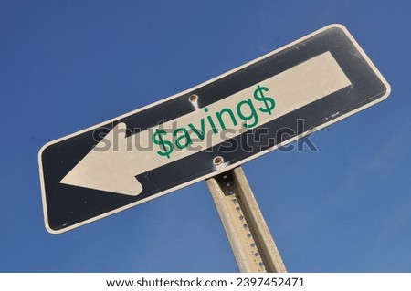 Inflation concept. One way sign pointing down with the word savings on it against a bright blue sky.