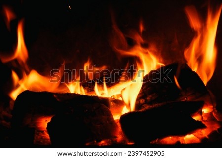 Burning log of firewood in fireplace. Close up abstract background Wood fire on black background