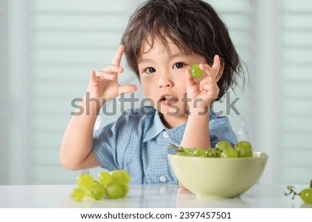 Happy little boy eat the grapes