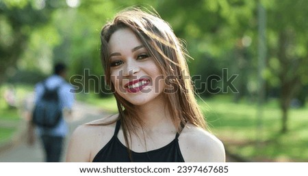 Pretty hispanic girl in 20s smiling to camera posing in park