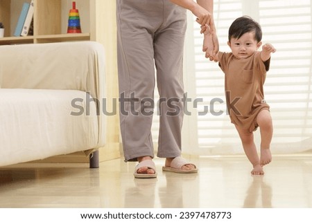 Young mother holding a baby learning to walk