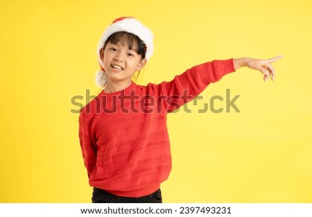 Image of an Asian girl wearing a Christmas sweater and hat posing on a yellow background