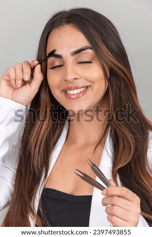 Young beautiful woman combing her eyebrow hair