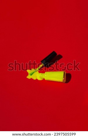 photo of neon nail polish spilling over a red background, studio photography