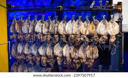 dried squid Bundles hung in rows. Each row is a different size. It is a snack, appetizer menu that is grilled and mashed until thin. Make it longer than before eating. Can be used as an illustration