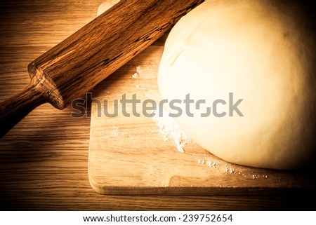 rolling pin and dough on a wooden table. slightly tinted