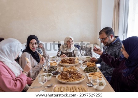 Family eating together with multi generation members in modern living room Royalty-Free Stock Photo #2397529255