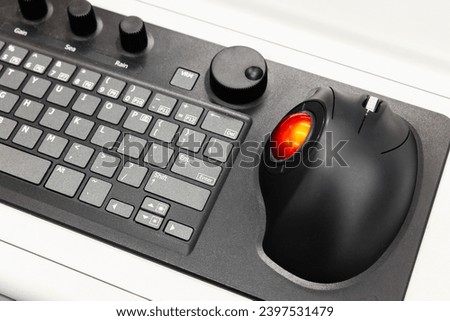 Built-in tabletop input device, black industrial keyboard with red trackball mouse, modern navigation equipment mounted on a control panel at captains bridge  Royalty-Free Stock Photo #2397531479