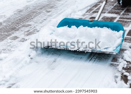 Cleaning snow from sidewalk and using snow shovel Royalty-Free Stock Photo #2397545903