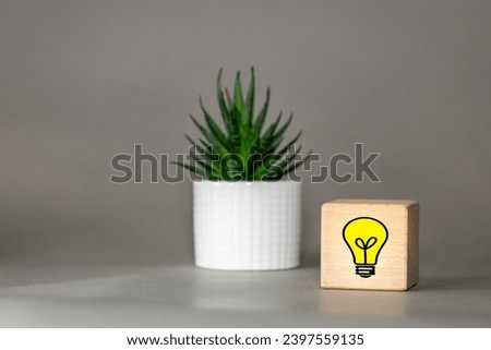 Creative idea concept, Light bulb Symbol of a new idea on a wooden block, next to it is a sequin standing on the desk, beautiful gray background, Conceptual business vision