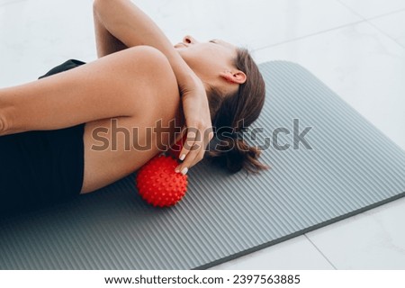 Woman lying on small balls to eliminate back pain, massage stiff muscles and thoracic back pain, perform exercises to relieve pain in spine. Relaxation and stretching of muscles Royalty-Free Stock Photo #2397563885