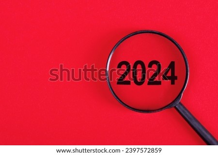 2024 inside of Magnifier glass on red background for focus current situation. 2024 present in focus business