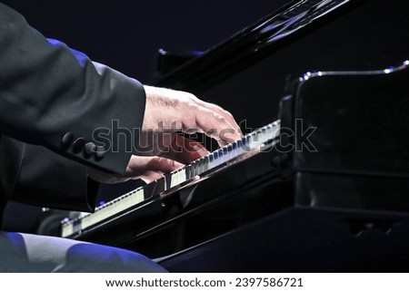 Pianist playing a grand piano on stage, close-up