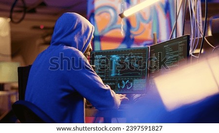 African american hooded hacker hiding in underground base, anxiously looking around for threats, feeling nervous after stealing data from victims using virus, trying hard to evade law enforcement Royalty-Free Stock Photo #2397591827