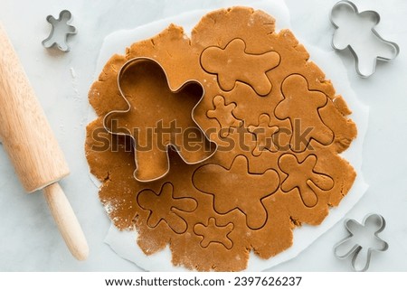 Gingerbread cookie dough rolled out and cut into gingerbread men. Royalty-Free Stock Photo #2397626237