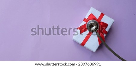 medical stethoscope with gift box isolated on a purple pastel background. concept christmas and new year.horizontal photo