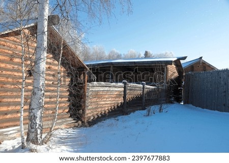 Winter rural landscape. View of fences with outbuildings on the village street