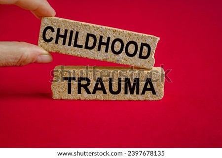 Childhood trauma symbol. Concept words Childhood trauma on brick blocks. Beautiful red background. Businessman hand. Business psychology childhood trauma concept. Copy space.