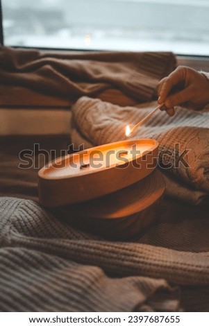 A match lights a candle in wood, stylish interior.
