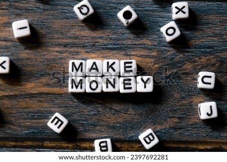 spelling of the word "make money" from alphabet blocks on wood texture background, concept and design for financial theme