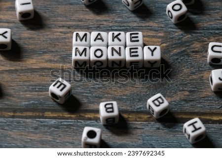 spelling of the word "make money" from alphabet blocks on wood texture background, concept and design for financial theme