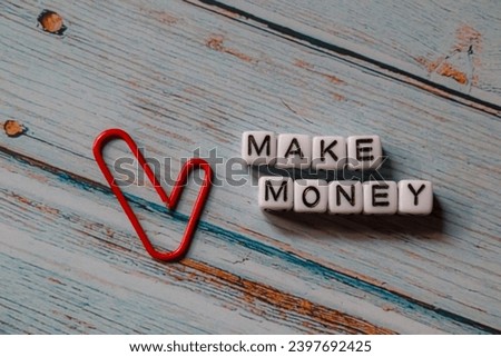spelling of the word "make money" from alphabet blocks on blue wood texture background, concept and design for financial theme