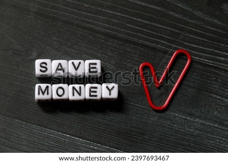 spelling of the word "Save Money" from alphabet blocks on dark wood texture background, concept and design for financial theme