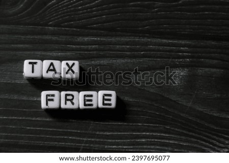 spelling of the word "Tax Free" from alphabet blocks on dark wood texture background with negative space