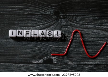 spelling of the word "INFLASI" from alphabet blocks on dark wood texture background, concept and design for financial theme