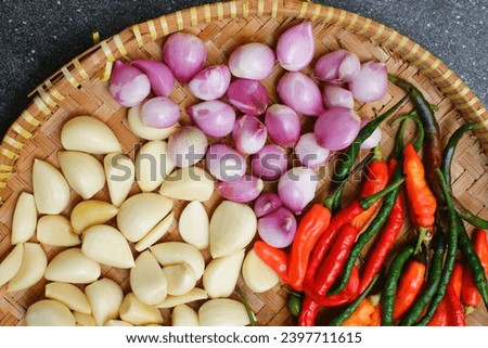 selective focus of fresh garlic, onion and chillies in a bamboo woven plate 