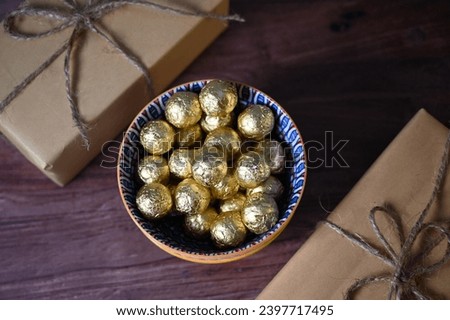 Round chocolate candies in a golden wrapper. Round candies. Golden color. A holiday gift. Birthday. Food photo. Sweet food. Happy birthday. Background image. Chocolate Top View.