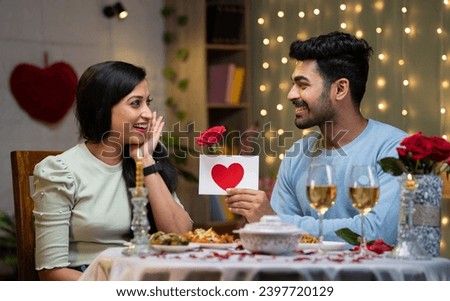 Happy girl excited by boyfriends proposal with red roses during candle light dinner at home - concept of valentines day, relationship and romantic couple. Royalty-Free Stock Photo #2397720129