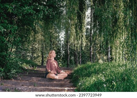 meditation Woman meditates in nature outdoor.At ground level, a relaxed woman meditates and breathes while sitting in Lotus pose next to fragrant incense during a yoga class in the garden