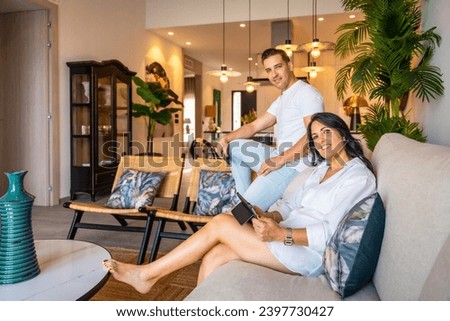 Portrait of a modern couple smiling at camera using tablet at home